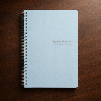 Light blue weekly planner with spiral binding on wooden surface
